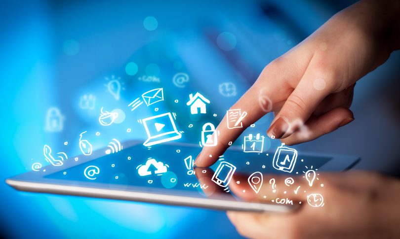 Close up of tablet with social icons in the air