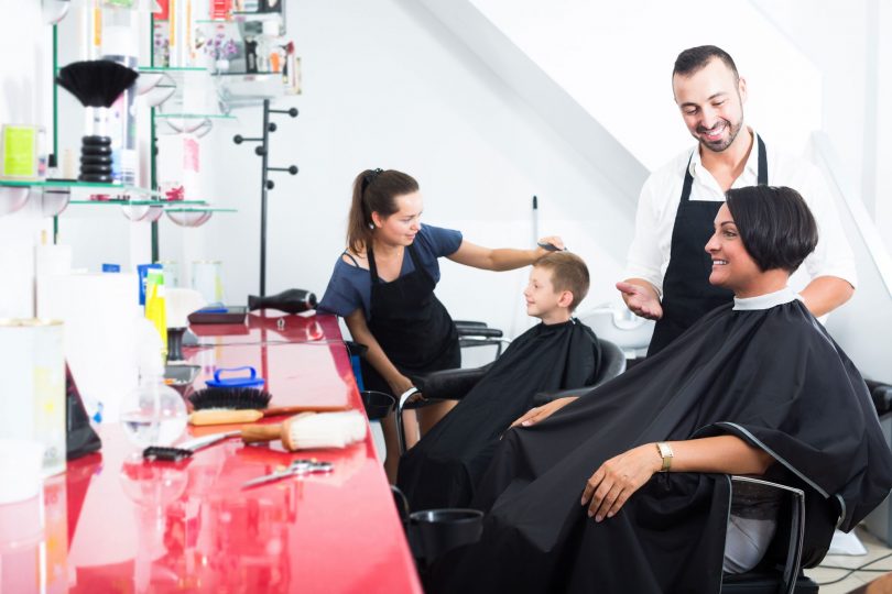 Mother and son in hairdressing chair talking to stylists