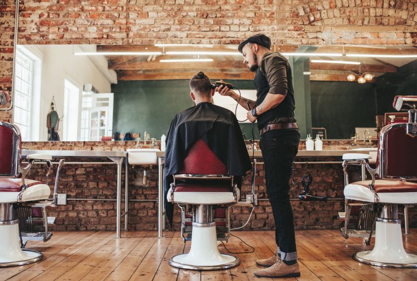 Client in barber's chair having hair cut with clippers