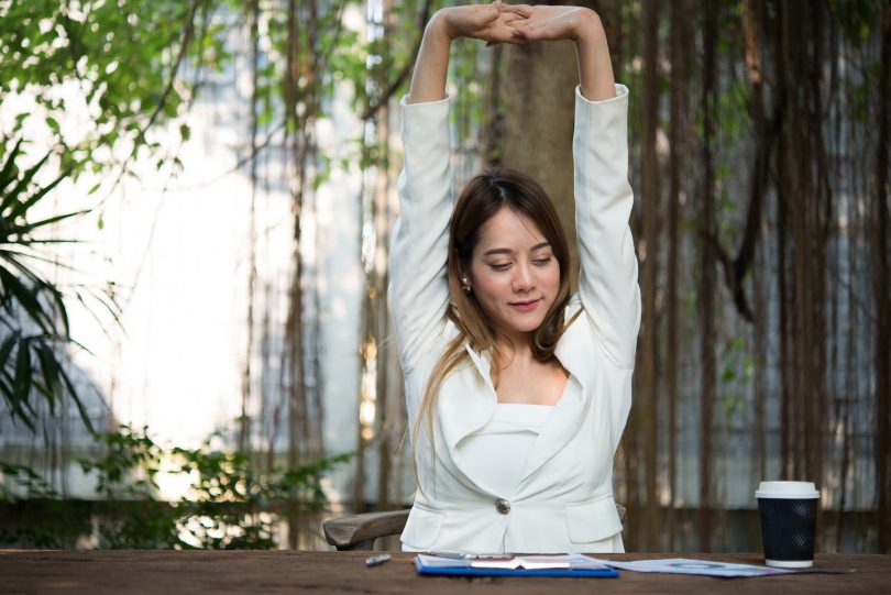 Lady stretching with greenery in background